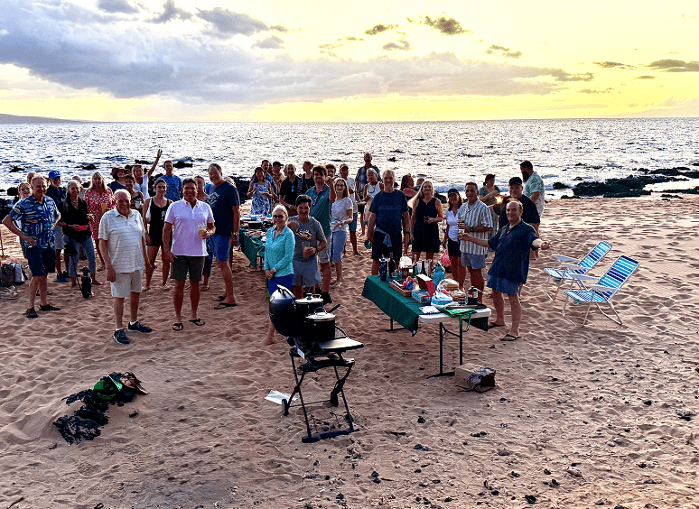 Crowd celebrating on sandy beach at dusk